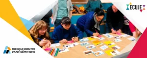 Bandeau Freque contre lantisémitisme 2 People gathered around a table arranging photos and colored notes for an anti Semitism awareness mural with a large geometric banner and logos in the background