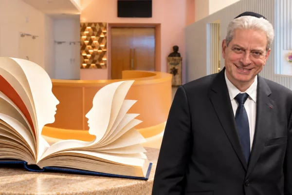 Moché Lewin dans l’accueil de l’ECUJE, près d’un livre ouvert évoquant deux profils en dialogue.